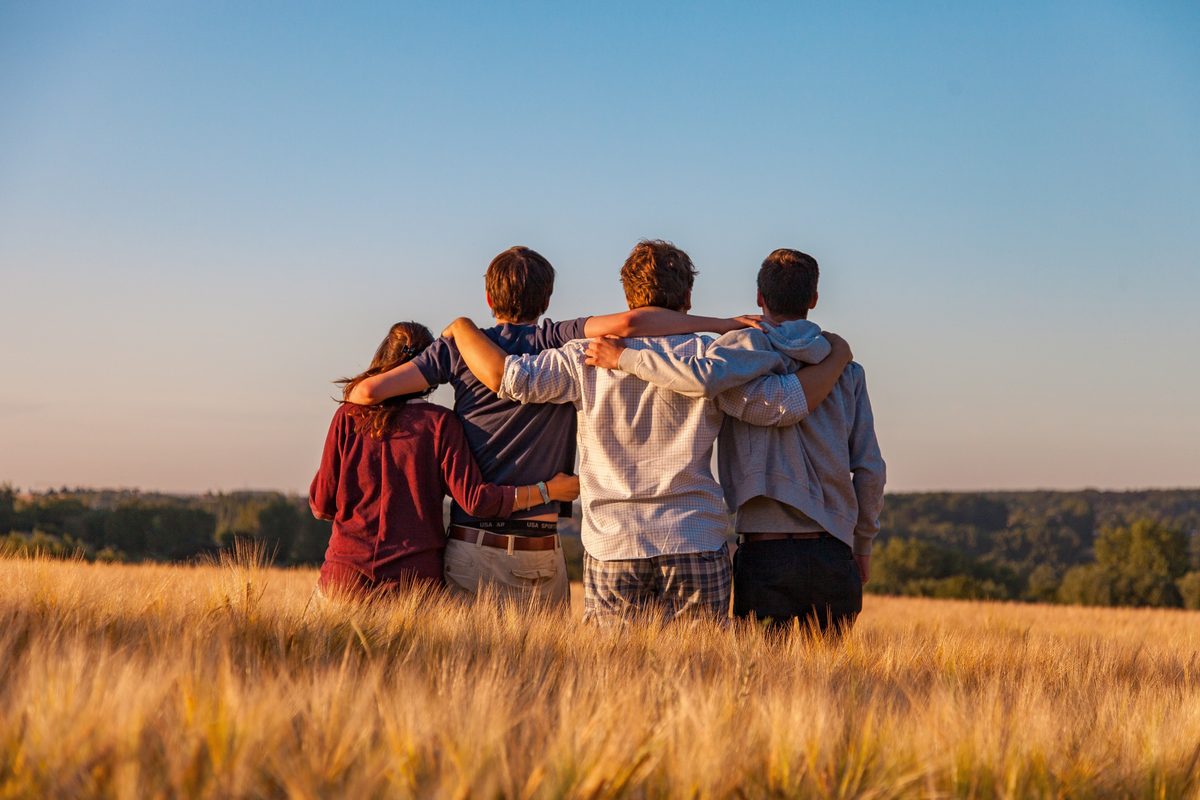 Vier jongeren samen in een veld bij zonsondergang